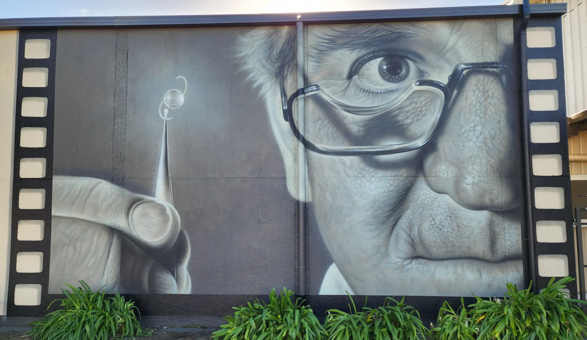 A painting of Fred Hollows holding a lens used in cataract surgery