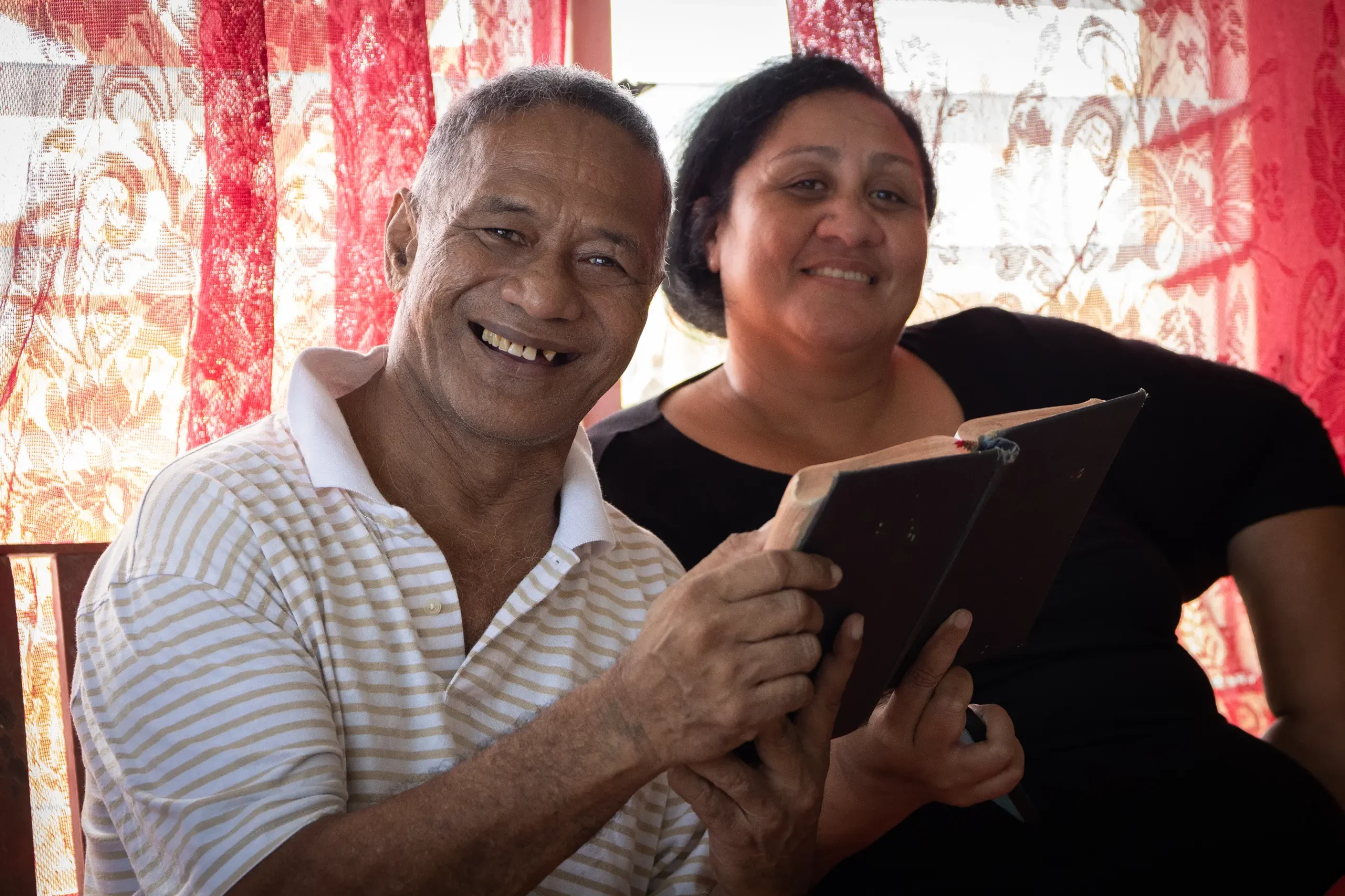 Pateki holding a bible and smiling next to his wife
