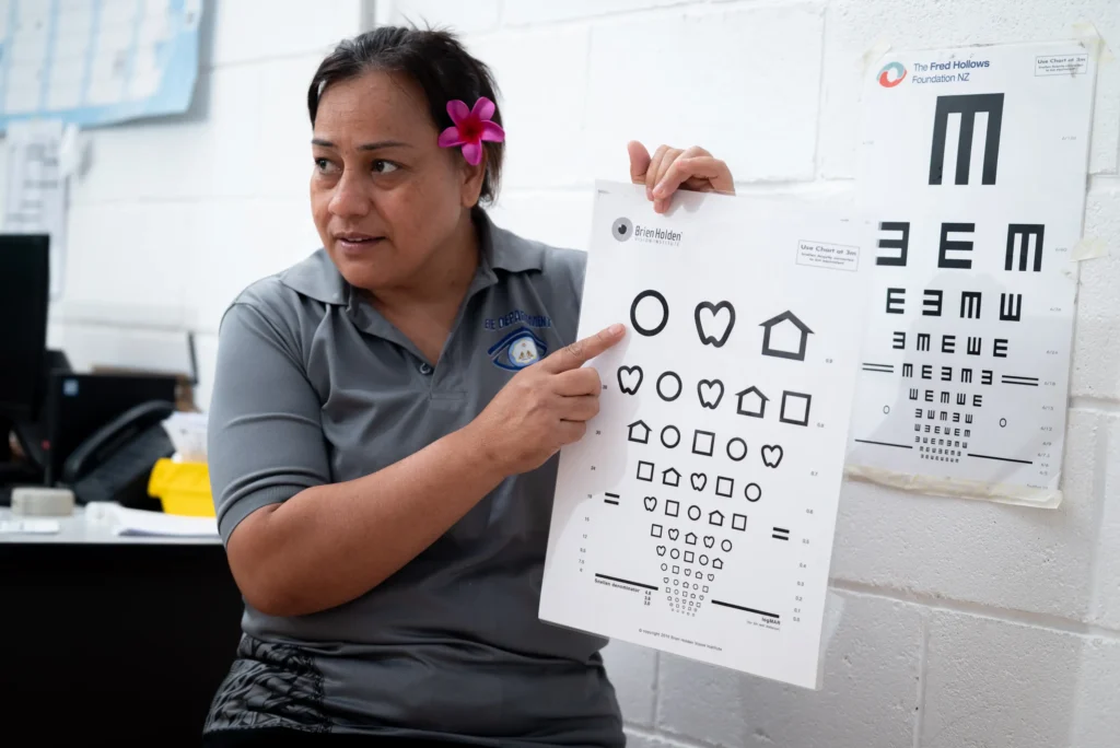 An eye nurse in Kiribati holds a symbol based eye chart