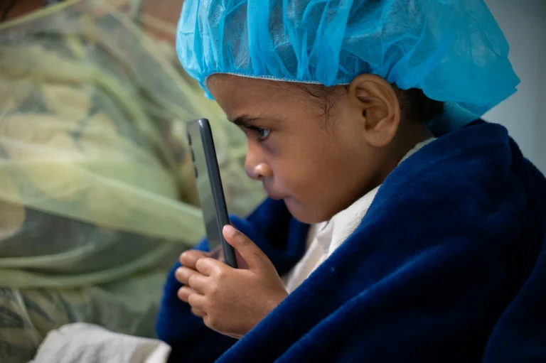 Philomena holding a screen close to her face to be able to see